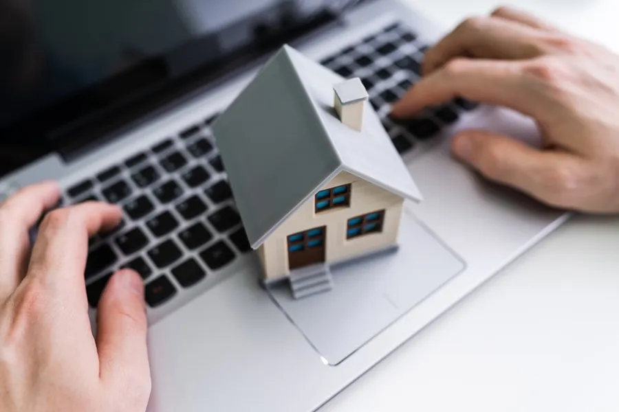 A miniature house sitting on a laptop keyboard