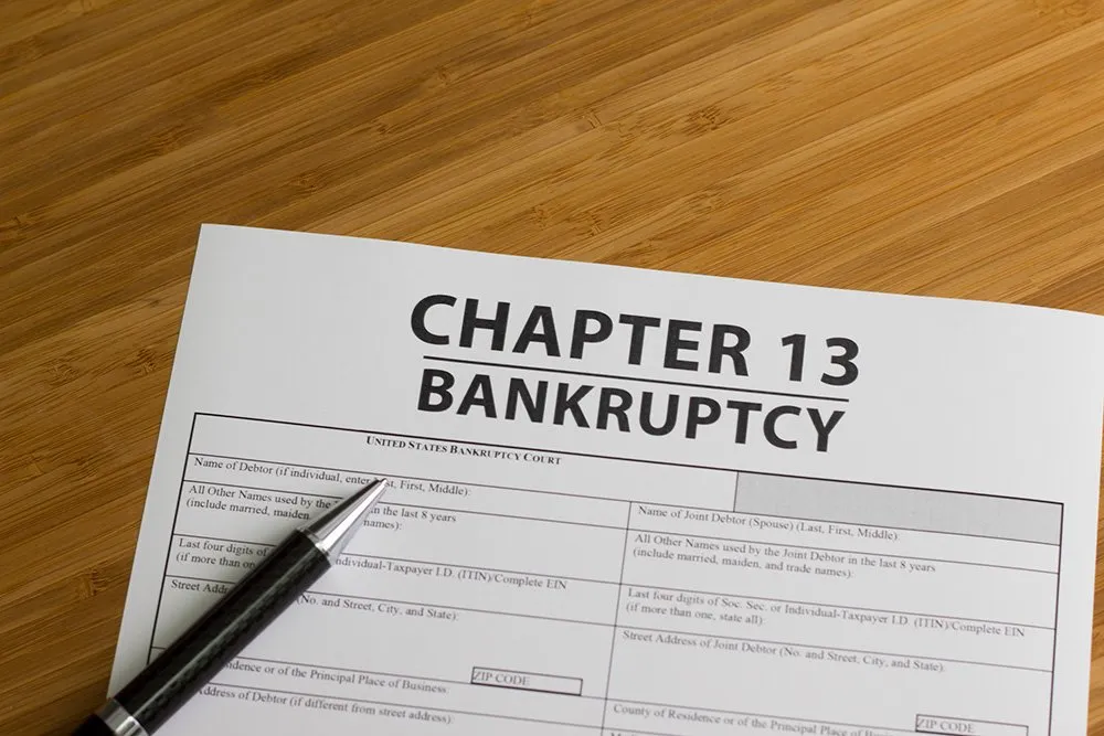 Chapter 13 bankruptcy form with a pen on a wooden table.