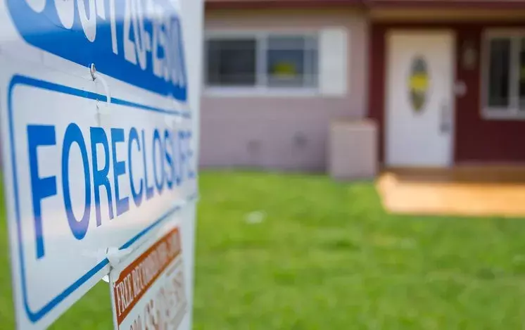 Front of a house with a "Foreclosure" sign posted