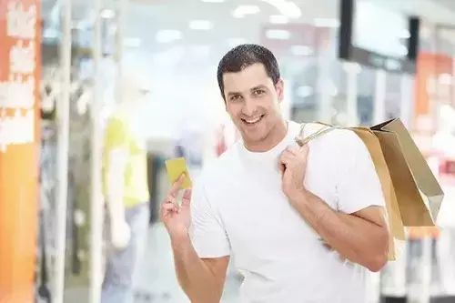 A man is depicted with a credit card and shopping bags, symbolizing a successful shopping experience after rebuilding his credit.